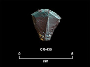 Fragment de pierre taillée rougeâtre et verte en forme d’hexagone allongé, avec un front convexe. La cote CR-435 et une échelle 0 à 5 centimètres sont inscrites en dessous.