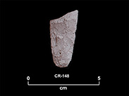 White chipped stone. Its shape is irregular, with a rounded base and divergent edges. The surface is altered. The number CR-148 and a scale of 1 unit:5 cm are shown below.