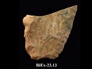 Fragment of beige chipped stone, with straight base and diverging edges. The top is broken at an oblique angle. The number BiEx-23.13 is inscribed on the bottom.