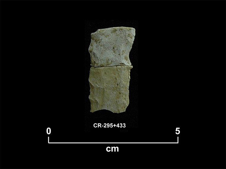 Deux éclats de pierre taillée beige, plus ou moins carrés, placés un au-dessus de l’autre. La cote  CR-295+433 et une échelle 0 à 5 centimètres sont inscrites en dessous.