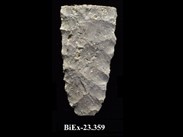 Fragment de pierre taillée blanchâtre de forme rectangulaire, avec une base arrondie et des côtés présentant des marques de taille. La cote BiEx-23.359 est inscrite en dessous.